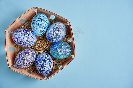 蓝宇宙鸡蛋就放在圆木篮子里 它站在蓝色背景上 蛋盒 烹饪图片
