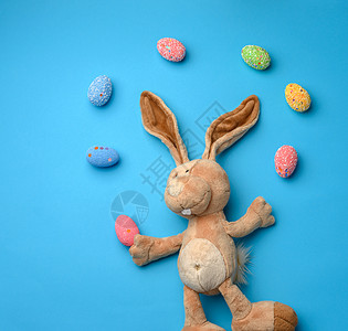 蓝色背景上长耳朵的装饰性复活节彩蛋和柔软的毛绒兔子玩具 传统的 黄色的图片