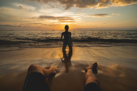 日落时在海滩上挂着男人的双腿 海浪 乐趣图片