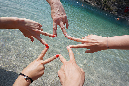 五只手在大海面前通过手指连接组成一个星形 快乐的朋友或家人度假 海滩假期概念图片