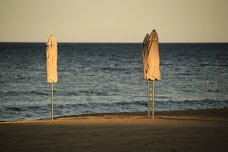 日落时沙滩上的海滩雨伞 晴天 旅行 假期 放松 游客图片