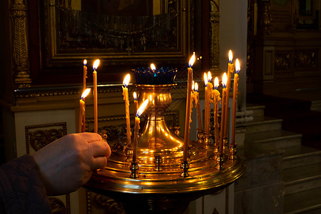 女人的手在教堂里点着蜡烛 复活节和圣诞节的概念图片