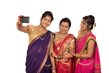 印度传统女孩在白色背景上用智能手机自拍的印度传统女孩 家庭 微笑图片