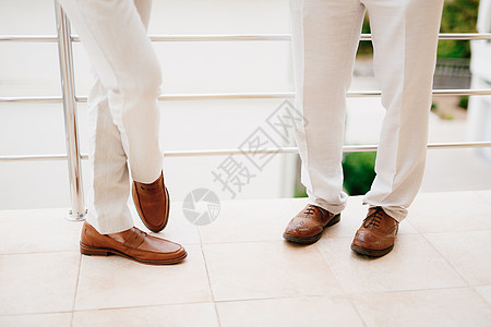 站在阳台上的两个男人的腿 特写 新郎和他的伴郎在准备婚礼期间图片