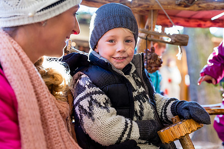 母亲和儿子在圣诞节市场上 还有旋转木马图片