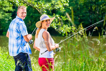 年轻夫妇在河岸捕鱼或钓鱼 或站立在河岸上 溪 运动图片
