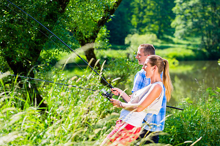 在河边钓鱼的男人和女人 加上棍子 溪流 活动图片