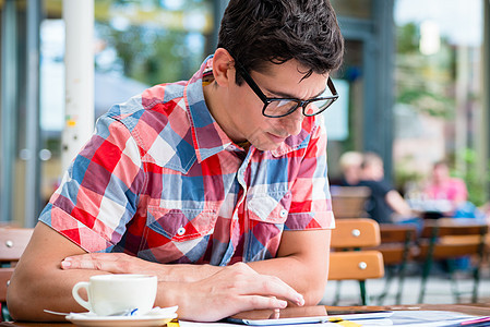 在街上咖啡馆喝咖啡的人在平板设备上阅读 软垫背景图片