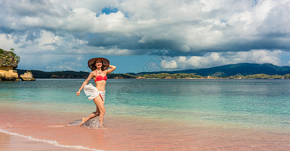 快乐的年轻女子在海滩上渡过浅海水 东南亚 科莫多图片