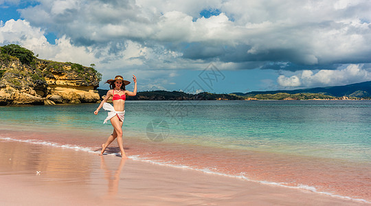 快乐的年轻女子在海滩上渡过浅海水 科莫多岛 云图片