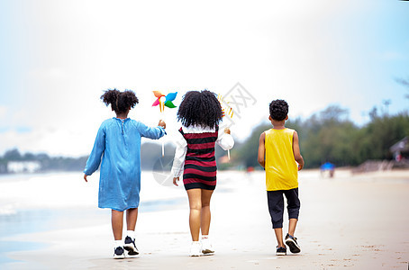 孩子们在沙滩上的沙滩上玩耍 一群孩子在夏天手牵着手在沙滩上排成一排 后视大海和蓝天 友谊 快乐的图片