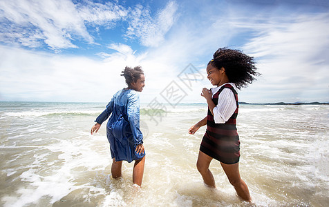 孩子们在沙滩上的沙滩上玩耍 一群孩子在夏天手牵着手在沙滩上排成一排 后视大海和蓝天 游泳衣 朋友图片