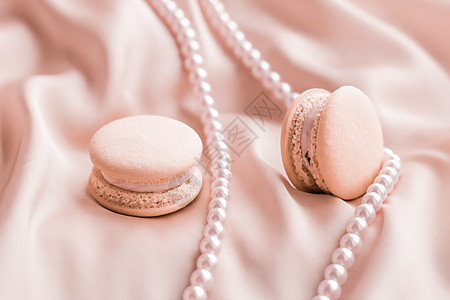 丝绸背景上的甜马卡龙和珍珠首饰 巴黎别致的珠宝 法式甜点食品和豪华糖果品牌的蛋糕马卡龙 节日礼物 织物 展示图片