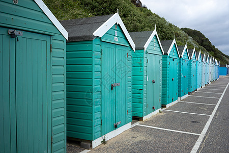 夏季阴天 在英国多塞特郡伯恩茅斯的林荫大道上 色彩缤纷的海滩小屋 绿色和蓝色图片