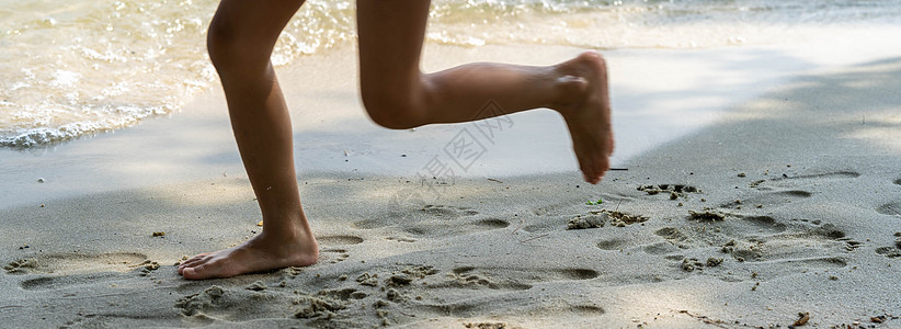 一个孩子沿着河岸边跑边用脚溅水 夏天 孩子在沙滩上玩耍 赤脚在沙滩上奔跑 海游 孩子们的脚在沙子里 闲暇 旅行图片
