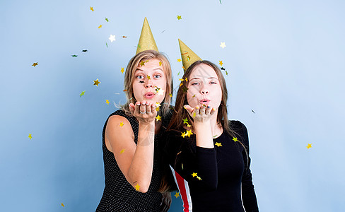 两个戴着生日帽子的年轻女青年 拿着气球 在蓝底上庆祝生日 派对 生日蛋糕图片