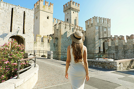 在意大利旅行 在西尔米奥奈 Sirmione 往斯卡利格罗城堡 走的女游客的背影 享受访问欧洲的女孩后视图图片