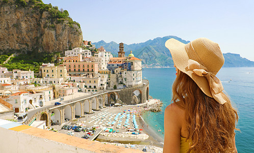 意大利暑假 意大利阿马尔菲海岸Amalfi村背景中带着草帽和黄色礼服与Atrani村的年轻女子背影 地标 浪漫的图片