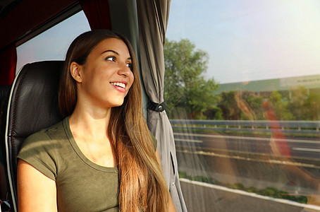透过公交车窗看年轻漂亮的女人 快乐的公共汽车乘客坐在座位上 透过窗户看 长的 车辆图片