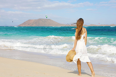 年轻女子在Corralejo野海滩上行走 在卡那利群岛的Lobos岛观望背景 头发 裙子图片