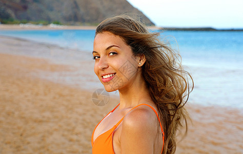 在海滩上的幸福女人 美丽的女孩的画像 头发随风飘扬 日落时在海滩上的夏日肖像 年轻漂亮的微笑女人户外肖像 棕褐色 日出图片