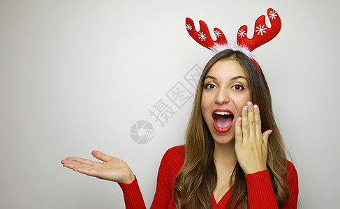 兴奋的年轻女士头部有驯鹿角 看着相机 用白色背景展示你的产品 复制空间 笑声 牛角 圣诞节图片