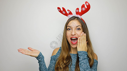 兴奋的年轻女士头部有驯鹿角 看着相机 用白色背景展示你的产品 复制空间 笑声 微笑 圣诞节图片