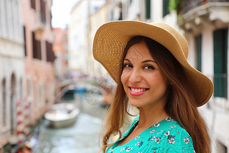 带着帽子和绿色礼服的微笑快乐女人的脚步 在意大利威尼斯 有魅力的女孩在摄影机上笑得开心极了图片