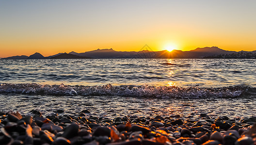 地中海沿岸美丽的夕阳 有岛屿和山丘 阳光照亮的海滩上的石块;以及 放松 晚上图片