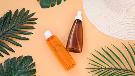 防晒霜 防晒帽 润滑剂瓶 在软橙色背景上 保护太阳 防晒系数图片