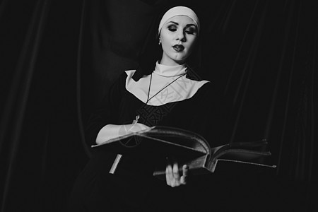 身穿宗教黑西装的美丽的年轻修女持有圣经 宗教概念 女孩 和平图片