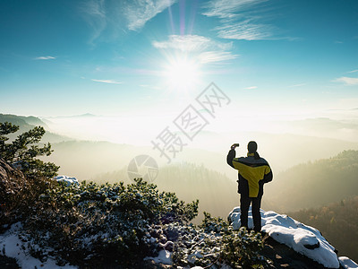 人类在冬季清晨 在岩石山脊的手机上拍摄照片图片
