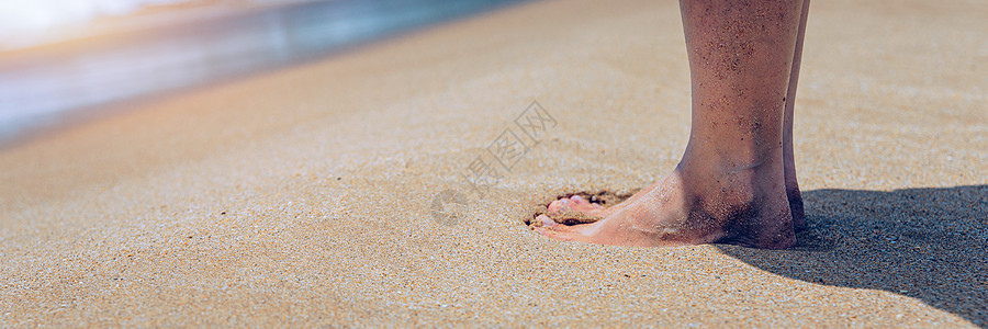 在站立在海边的少妇的腿的特写镜头 女人的腿和脚在沙滩上行走 背景是海水 女人站在波浪海的沙滩上 假期 放松图片