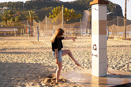 一个穿短裤的女孩 和一件黑色T恤 在海滩附近的淋浴图片