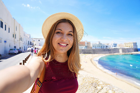 快乐的年轻女性通过智能手机拍摄暑假旅行片段 自拍自己照片图片