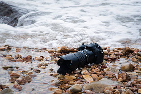 DSLR 在海浪下浸湿的石沙滩上的德国航天中心照相机 住房 单反图片