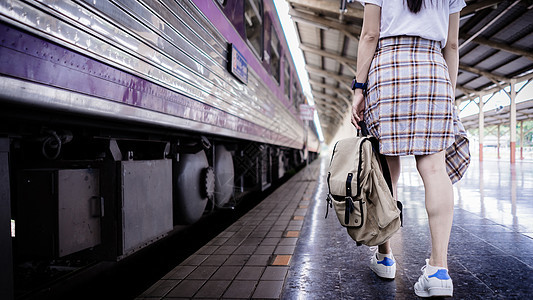 背着背包的年轻女性旅行者在火车站行走 在铁路站台上等火车 旅游概念图片