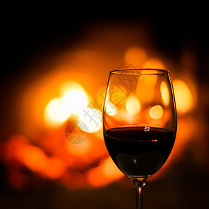 在壁炉灯下 一杯红酒在壁炉灯的背面 葡萄酒 火热图片