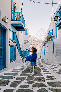 希腊米科诺斯岛 希腊小威尼斯米科诺斯岛度假期间在米科诺斯老城街道上穿着裙子的年轻女子 风车 夏天图片