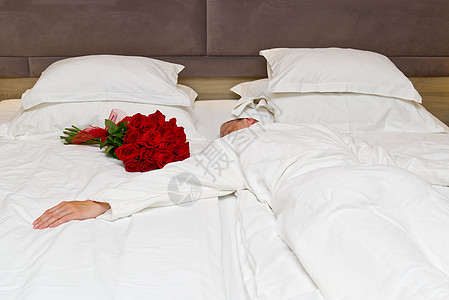 婚礼酒店在酒店蜜月房间的床上 盛放红玫瑰 在酒店举行浪漫的客人会议 笑声 幸福 花的背景