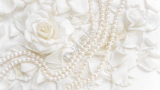 美丽的白玫瑰和珍珠项链 放在花瓣背景上 为婚礼 生日 情人节 母亲节的贺卡提供理想 浪漫的 浪漫图片