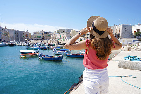 在Apulia的假日 女游客戴帽子后仰望着意大利Apulia的Giovinazzo美景港 船 海图片