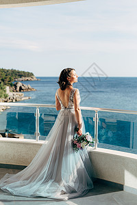 穿着漂亮婚纱的新娘 站在阳台上俯视大海 仰望着大海图片
