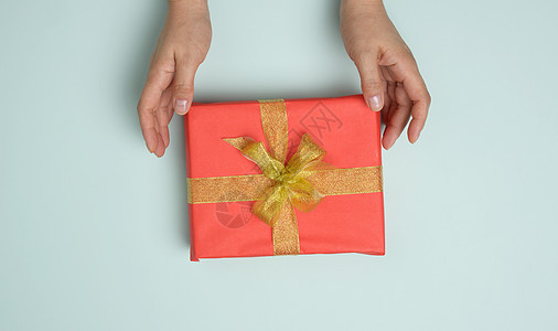 女性手拿着红色礼物盒 在蓝色背景上 祝贺的观念在生日时 掌声 图片