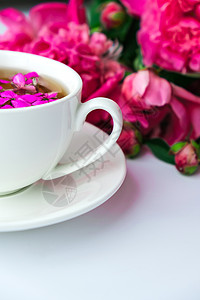 明亮的桌子上有粉色牡丹花和一杯茶的创意布局 春季季节性情人节 女人 母亲 3 月 8 日假期 浪漫早餐 时尚博主 问候卡 盛开 图片