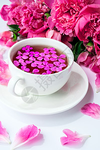 明亮的桌子上有粉色牡丹花和一杯茶的创意布局 春季季节性情人节 女人 母亲 3 月 8 日假期 浪漫早餐 时尚博主 问候卡 开花 图片