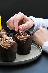 女性亲手制作美味巧克力蛋糕 奶油夹在黑暗背景上 三份巧克力松饼 生日蛋糕晚会的准备 曲奇饼 派对食物图片