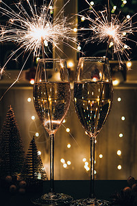 两杯带烟火的起泡酒香槟 深色背景与黄光散景 桌上的圣诞树玩具 新年孟加拉冷杉 浪漫 红酒杯背景图片