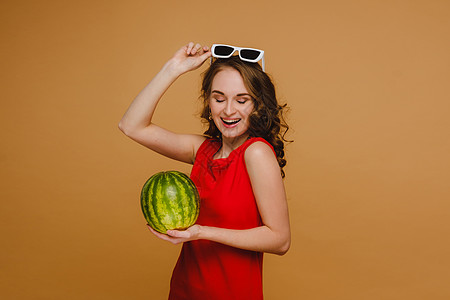 一个戴着眼镜的漂亮女孩 和红裙子 手里握着西瓜 饮食 夏天图片