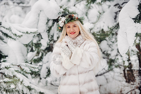 在寒冷的冬天森林里穿着白色皮草大衣的女人的画像 在白雪覆盖的冬季森林里 头戴花环的女孩 花园 新年图片